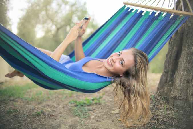 cheerful young woman resting in colorful hammock